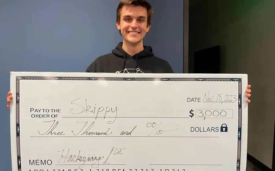 A student holding a $3,000 first-place check
