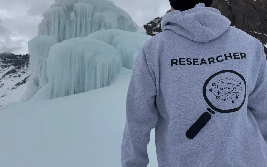 A student in a MAIC Researcher hoodie in front of an ice stupa